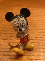 Close-up of Mickey Mouse figurine front showing crystal detailing on face and body, black enamel ears, and red shorts.