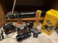 Vintage 35mm cameras including Olympus, Canon and Ward along with Vivitar zoom lens, camera straps, tripod, film rolls, and film to digital converter