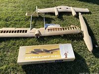 Overview photo showing two wooden glider planes components and Duellist 240 model kit box with parts inside.