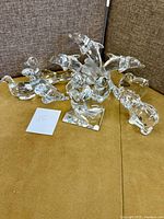 Nine clear crystal animal figurines including dolphins, birds, elephant on brown surface