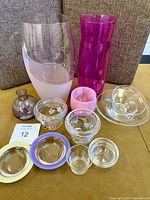 Photo showing the entire collection of colorful art glass pieces including vases, bowls, and small dishes arranged on a surface.