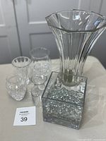 Photo showing the full 5-piece lot including the large flared vase, three smaller clear glass vases, and the square glass bowl filled with marbles.