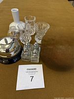 Overview of lot showing the four miniature decorative vases, four salt and pepper shakers with metal tops, and a small service bell on a soft brown surface.