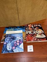 Three hardcover art books laid on wood surface: Van Goghs by Abrams, Masterpieces of the J. Paul Getty Museum, and Understanding Picasso.