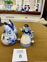 Front view of the milkmaid bell and pear-shaped candle holders on a table with kitchen background.
