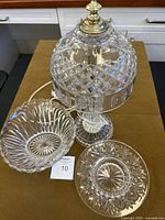 Cut glass crystal table lamp with diamond and oval cut pattern shade and fluted base, two matching decorative bowls with ribbed swirl and starburst patterns.