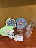 Full view of lot including vintage Princess House chip and dip bowl, two decorative plates, green Tupperware mold, two small ceramic pitchers, a clear glass vase, and four small glass decanters with stoppers.