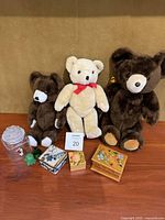 Photo of three vintage teddy bears standing upright on a shelf with three trinket boxes, clear glass jar with frog lid, and small green turtle and frog figurines in front.