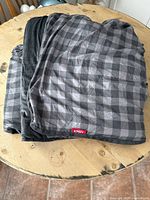 Weighted blanket folded on a wooden table showing the gray plaid pattern and ENDY tag.