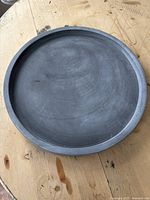Top-down view of gray round tray, showing flat surface and raised edge.