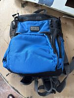 Front view of blue Outward Hound backpack carrier with padded straps, zippered compartments, and mesh side panels.