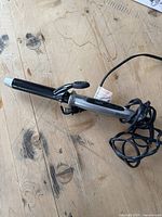 Curling iron full view showing barrel, clamp, handle, and cord.
