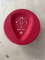 Red Pelvic Clock device, top view showing clock face markings and pelvic graphic