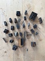 Photo of assorted vintage printing tray letters scattered on wooden surface showing various uppercase letters in wood and metal.