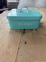 Front view of mint green metal tea canister labeled 'TEA BAGS'