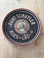 Front of the round metal beer tray showing the Fort Schuyler Ales and Lager logo with Utica Brewing Co. emblem and text.