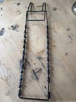 Full view of vintage metal note holder showing rectangular stand frame and two parallel metal rods with multiple clips attached.