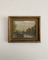Front view of the oil painting showing the landscape scene and gold toned wooden frame with some paint chipping.