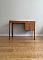 Front view of full teak desk showing rectangular top, four legs, and three drawers on right.