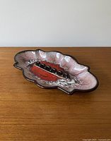 Front angle view of mid-century ceramic ashtray with organic shape and colorful glaze