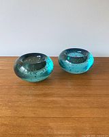 Pair of round blue bubble glass vintage candle holders shown on wooden surface