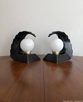 Front view of both lamps unlit on wood table against white wall