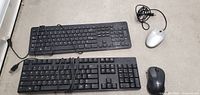Overview of two wired Dell keyboards and two mice (one wired silver Dell mouse and one black wireless Logitech mouse) on floor surface