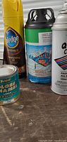 View of multiple paint cans and spray paint bottles showing brand labels and condition