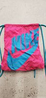 Front view of pink Nike drawstring bag with teal logo showing the overall design and condition.