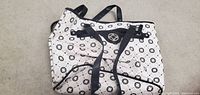 Front external view of white and black printed pleather tote bag with black handles and pattern.