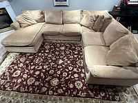 Full view of beige Bernhardt sectional couch with chaise showing cushions and pillows arranged on a patterned rug.