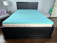 Front view of black pine bed frame with mattress and foam topper