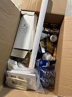 Box containing a variety of light bulbs in original packaging and loose, along with some outlet covers.