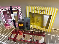 Photo showing all six items in the lot arranged on a shelf: Bath Haus soap and cream set, Giorgio Beverly Hills set, David Beckham and Bvlgari eau de toilette boxes, and three wrapped soaps with ribbon.