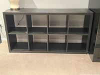 Two IKEA Kallax black shelving units shown empty, side by side displaying 8 open cubbies each.
