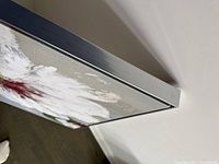 Close-up of thin silver contemporary frame on side of framed floral print artwork.