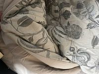 Displayed bedding in beige and grey floral embroidery.