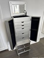 Front view of cabinet with top lid open showing mirror, central drawers closed, and side doors open