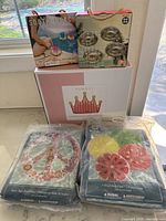 Overall shot showing the box of the crown lounger, packaged peace sign and fruit slice floats, and the drink holder mini floaties box on top