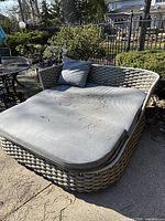 Full view of curved woven rope day bed with mattress cushion and pillow, outdoor setting