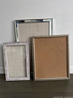 Three framed bulletin boards leaning against a wall showing size and frame differences.