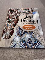 Cover of the Art Therapy Colouring Book showing detailed animal illustrations (zebra and wolf) in intricate patterns. Book is new and unopened with no coloring done inside.