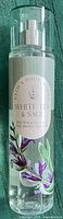 Front view of a new Bath & Body Works White Tea & Sage fragrance mist in a clear plastic bottle with a spray nozzle and transparent cap. The label shows the scent name with floral artwork.