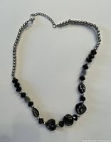 Black and silver beaded costume jewelry necklace laid flat showing the beading pattern and chain extending clasp