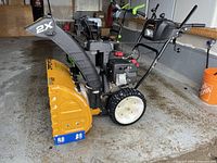 Side view showing entire snow blower, housing, auger, wheels and handle assembly
