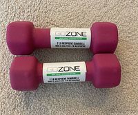 Photo shows two maroon 2 lb GoZone neoprene dumbbells side by side on a carpeted floor, each labeled with weight and brand.