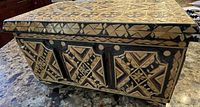 Box exterior showing geometric pattern on sides and top in natural wood and black tones.