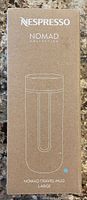 Packaging box of the Nespresso Nomad Collection Travel Mug showing product name, brand, collection, and line drawing of the mug.