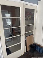 Pair of used solid wood 5-pane doors leaning against wall, showing front sides with glass panes and metal knobs.