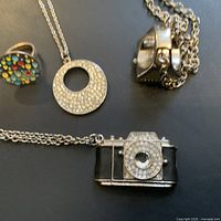 Four pieces of contemporary costume jewelry including two rings and two necklaces with unique pendants.